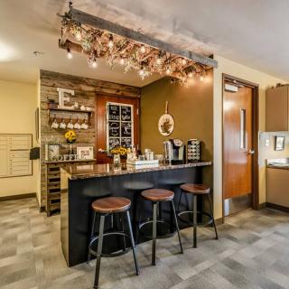 A modern kitchen with a cozy bar area featuring sleek stools, ambient lighting, and wine storage.