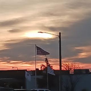 A beautiful sunset with a flag waving in the foreground.