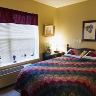 A cozy bedroom with a large bed, colorful bedding, and art on the walls.