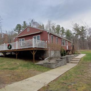 A cozy cabin with a large deck nestled in a rural, wooded area.