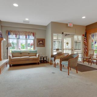 A cozy living room with a sofa, chairs, and large windows.
