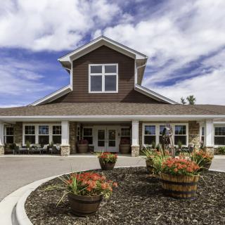 A residential building with a landscaped entrance and cloudy sky.