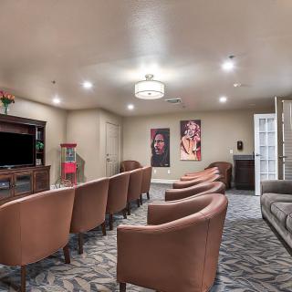 A cozy home theater room featuring comfortable seating, a large television, and movie-themed decor.