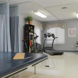 A rehabilitation room equipped with a treadmill and treatment table for physical therapy.