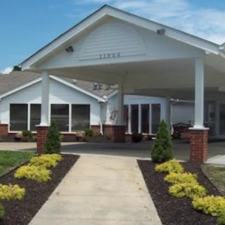 A building entrance with a pathway surrounded by landscaped greenery.
