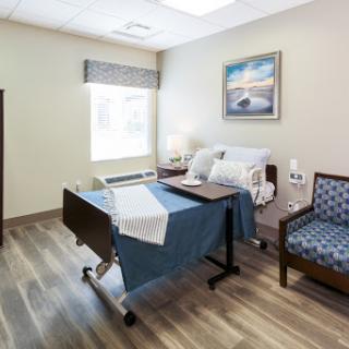 A well-lit and comfortable hospital patient room equipped with essential furniture.