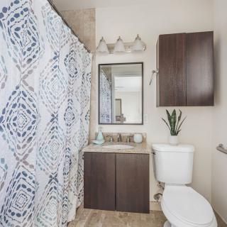 A modern bathroom with a patterned shower curtain and dark wood cabinetry.