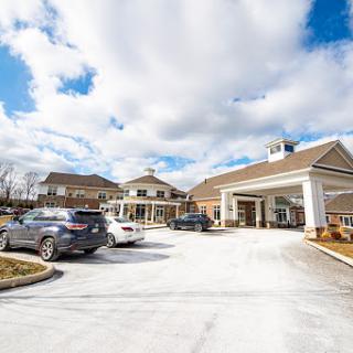 A view of a residential building with a parking area under a cloudy sky.