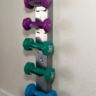 A rack of colorful dumbbells organized in a home gym setting.