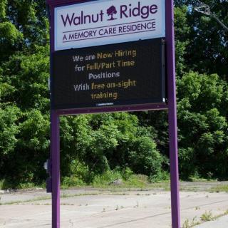 An outdoor sign for Walnut Ridge Assisted Care Residence with information about their services.