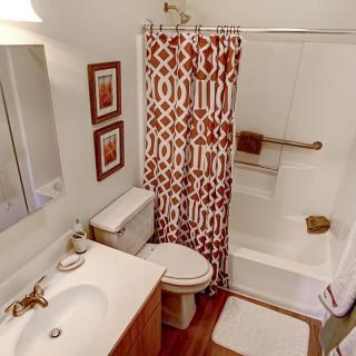 A cozy bathroom with a patterned shower curtain and wooden accents.
