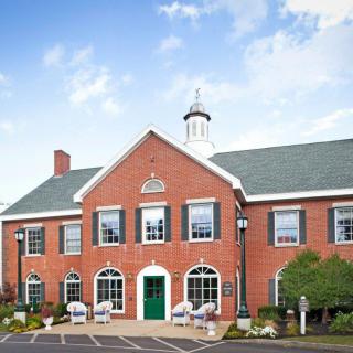 A brick building with a green door and multiple windows, likely a school.