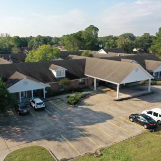 Aerial view of a suburban building with a parking lot and surrounding greenery.