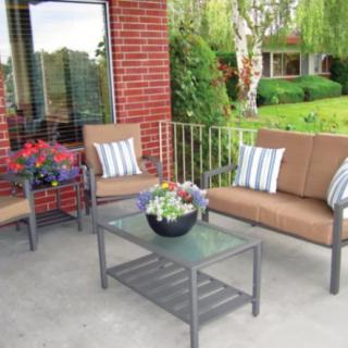 A cozy outdoor patio setup with chairs, a table, and potted plants against a brick wall.
