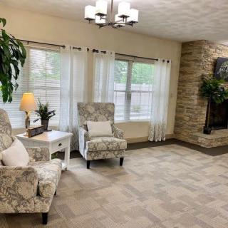 A cozy living room with patterned chairs and a stone fireplace.