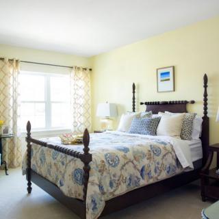 A cozy bedroom with a large bed, decorated with floral bedding and soft lighting.