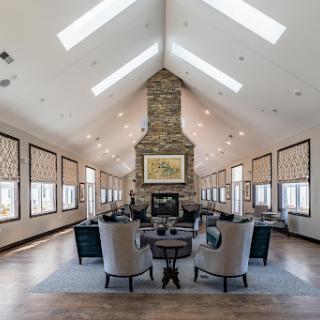 A spacious and modern living room featuring a striking stone fireplace and ample natural light from the skylights.