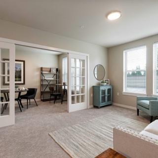 A modern living room with natural light, featuring French doors and stylish decor.