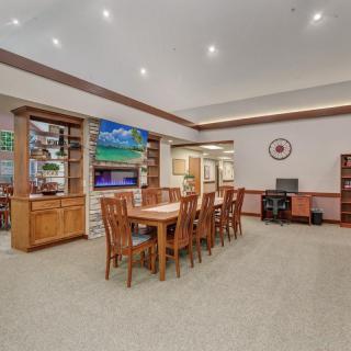 Spacious living area with a dining table, chairs, and a television, complemented by shelves and a computer desk.