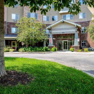 A hotel entrance with a pathway surrounded by greenery and trees.