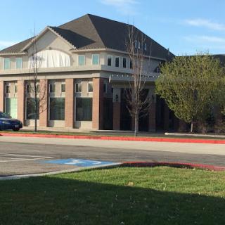 A modern building surrounded by a well-maintained lawn and parking area.