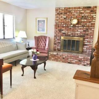 A cozy living room featuring a brick fireplace, a sofa, an armchair, and a coffee table.