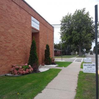 A view of a brick building with well-maintained landscaping and a sidewalk.