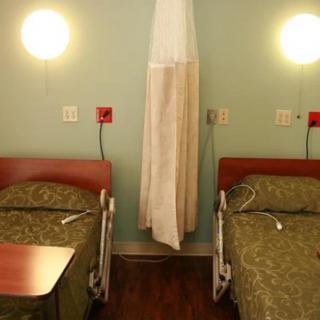 A hospital room with two beds separated by a curtain.