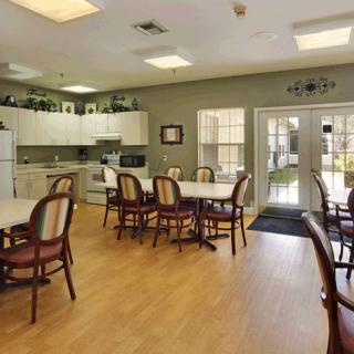 A spacious dining area with tables and chairs adjacent to a kitchen.