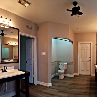 A modern bathroom featuring elegant lighting, a spacious mirror, and wood-style flooring.