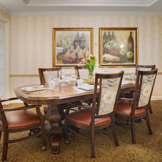 An elegant dining room featuring a wooden table set with chairs and framed artwork on the walls.