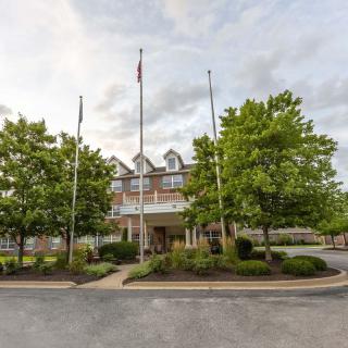 A hotel building with flags at the entrance, surrounded by trees and landscaping.