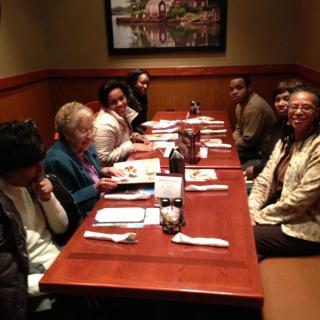 A group of people gathered around a table at a restaurant, enjoying each other's company.