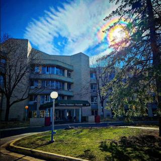A modern building framed by vibrant clouds and greenery under a bright blue sky.