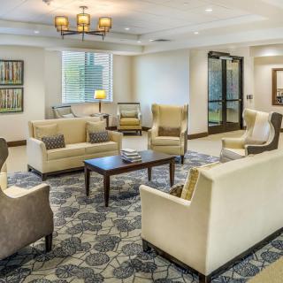 A cozy lobby seating area with armchairs and a coffee table under warm lighting.