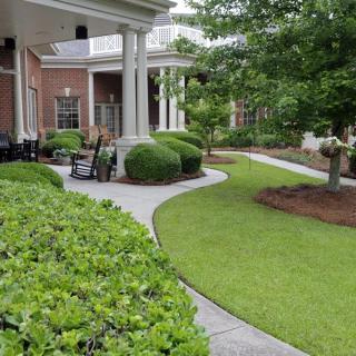 A beautifully landscaped outdoor area with a lush green lawn, carefully trimmed shrubbery, and a winding pathway.