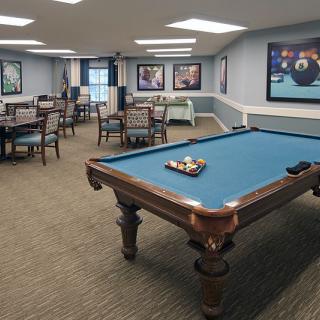 A well-furnished game room featuring a pool table and several seating areas.