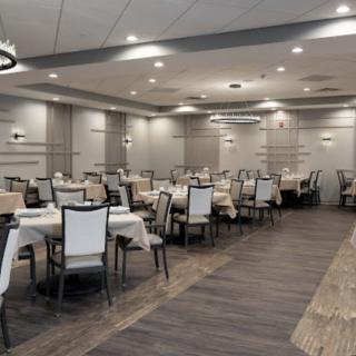 An elegant restaurant dining area with neatly arranged tables and chairs, featuring modern lighting.