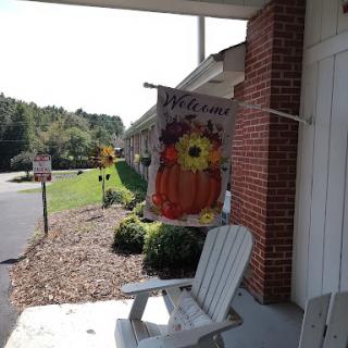 A welcoming autumn-themed flag featuring sunflowers and a pumpkin, displayed on a cozy porch.