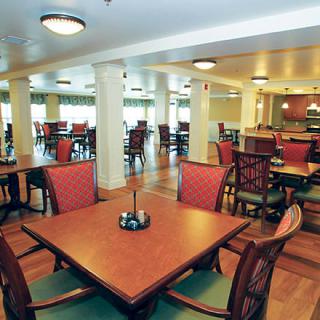 A spacious dining area with neatly arranged tables and chairs, featuring soft overhead lighting.