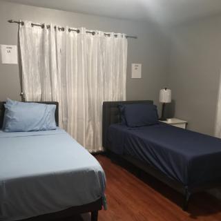 A small bedroom with two twin beds, a nightstand, and a lamp.