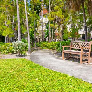 A serene park with a bench and pathway surrounded by lush trees and greenery.
