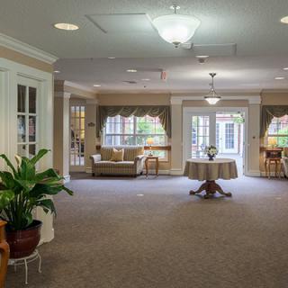 A spacious and elegantly decorated living room with comfortable seating, large windows, and indoor plants.