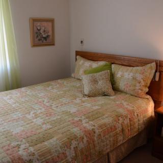 A cozy bedroom with a neatly made bed featuring a floral quilt and matching pillows.