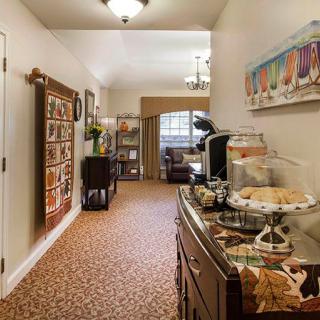 A cozy hallway with a snack and coffee station, decorated with artwork and carpeted flooring.