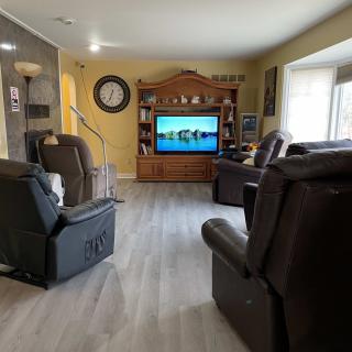 A cozy living room with recliner chairs facing a large television in an entertainment center.