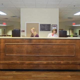 A reception desk with two staff members in an office setting.