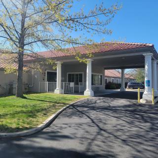 A building with a driveway and columns on a sunny day.