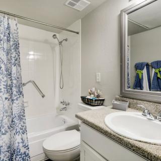 A modern bathroom with a shower curtain, sink, and mirror.