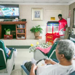 Elderly individuals in a nursing home enjoying leisure time with television and popcorn.
